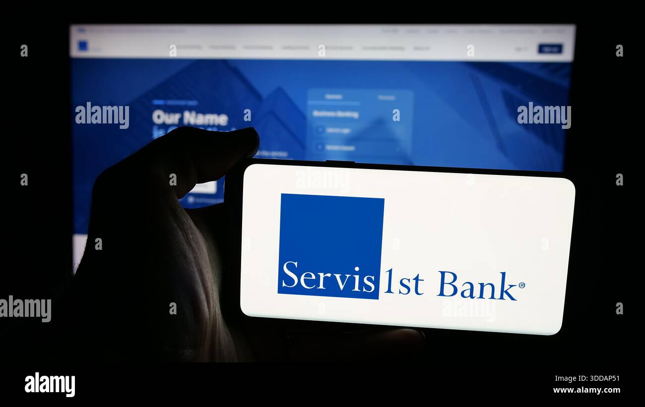 Stuttgart, Allemagne - 12-12-2025 : personne tenant un téléphone portable avec le logo de la banque américaine ServisFirst Bancshares Inc sur l'écran devant la page web. Banque D'Images