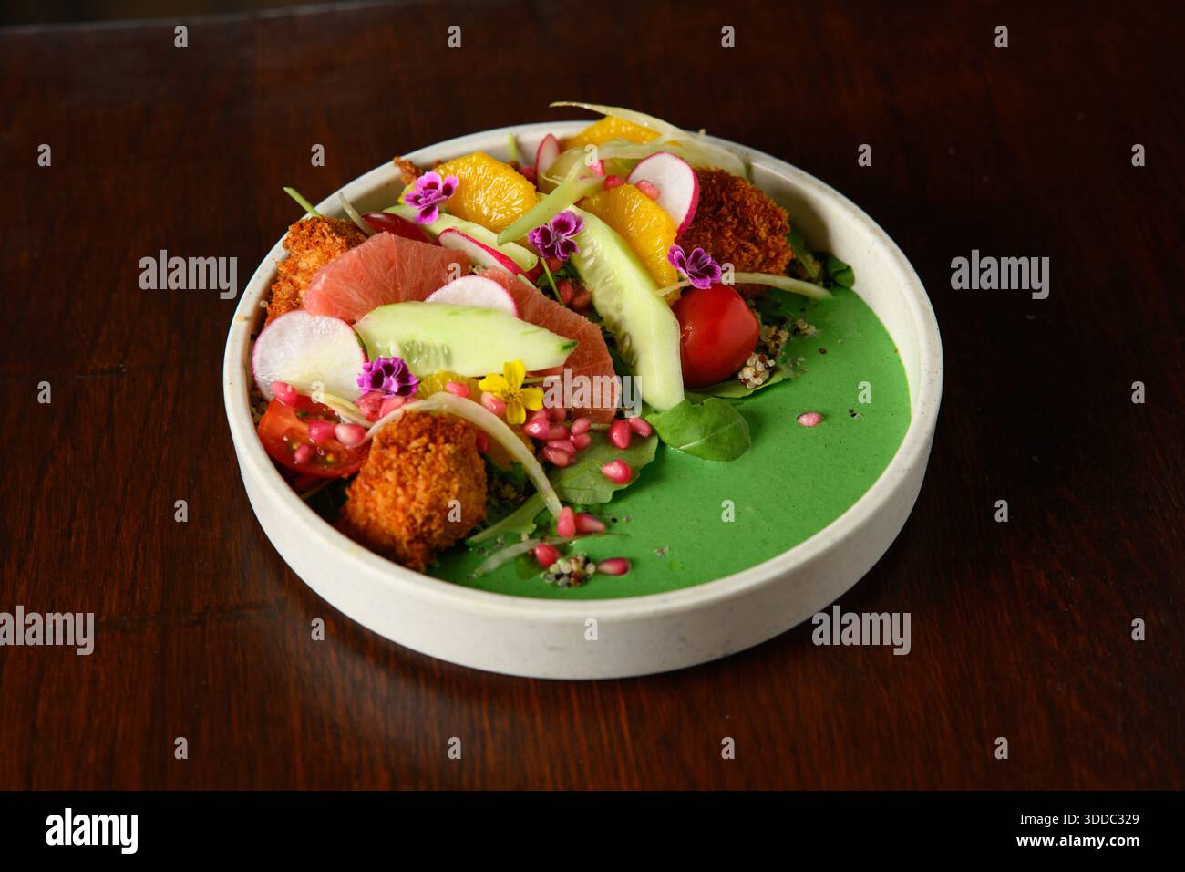 Une assiette de nourriture avec une base verte et une variété de fruits et légumes. L'assiette est sur une table en bois Banque D'Images