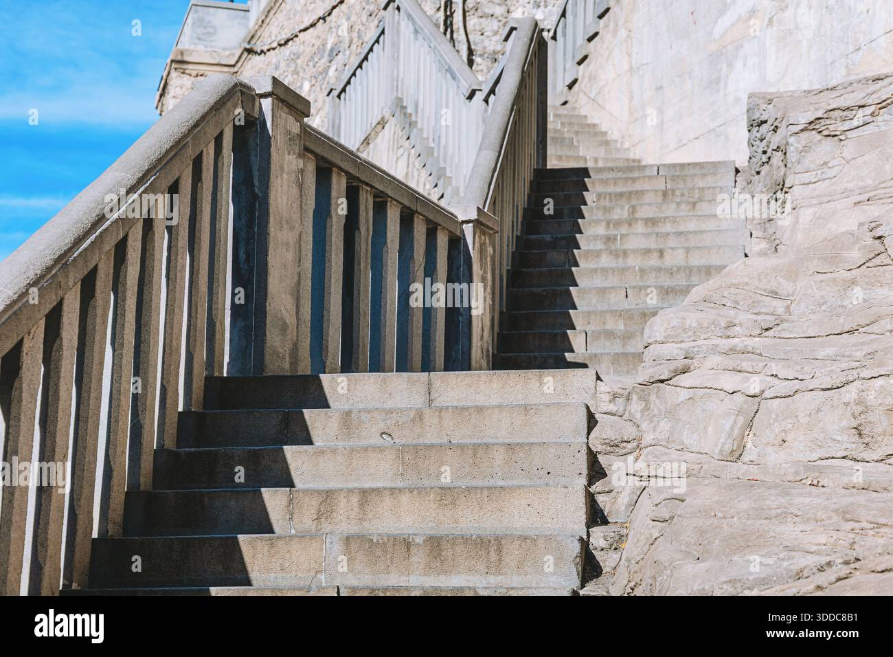 Escaliers extérieurs en béton montant, avec une forte lumière du soleil projetant des ombres géométriques sur les marches et les balustrades, montrant la conception de l'architecture Banque D'Images