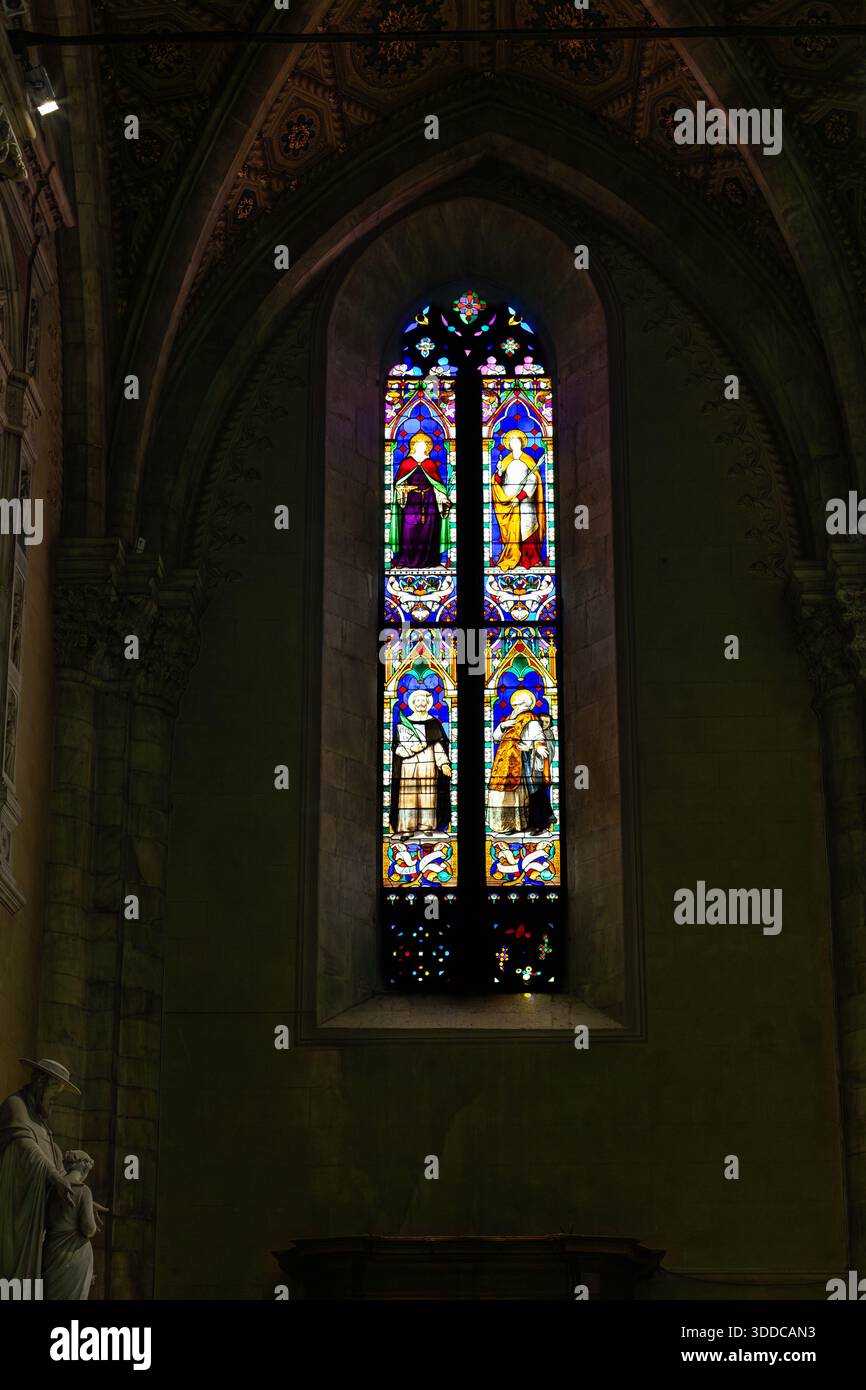 Un grand vitrail vibrant dans un intérieur d'église gothique, projetant une lumière colorée sur les murs de pierre. La scène transmet la vénération, la foi et le timel Banque D'Images