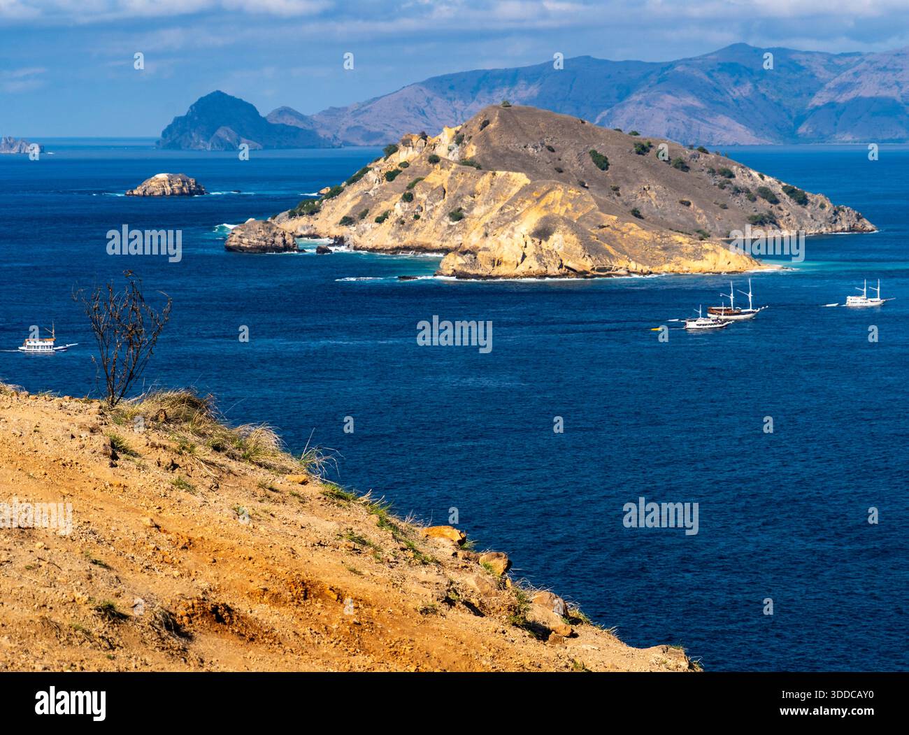 Vue panoramique d'une île rocheuse entourée par l'océan bleu avec des bateaux. Banque D'Images