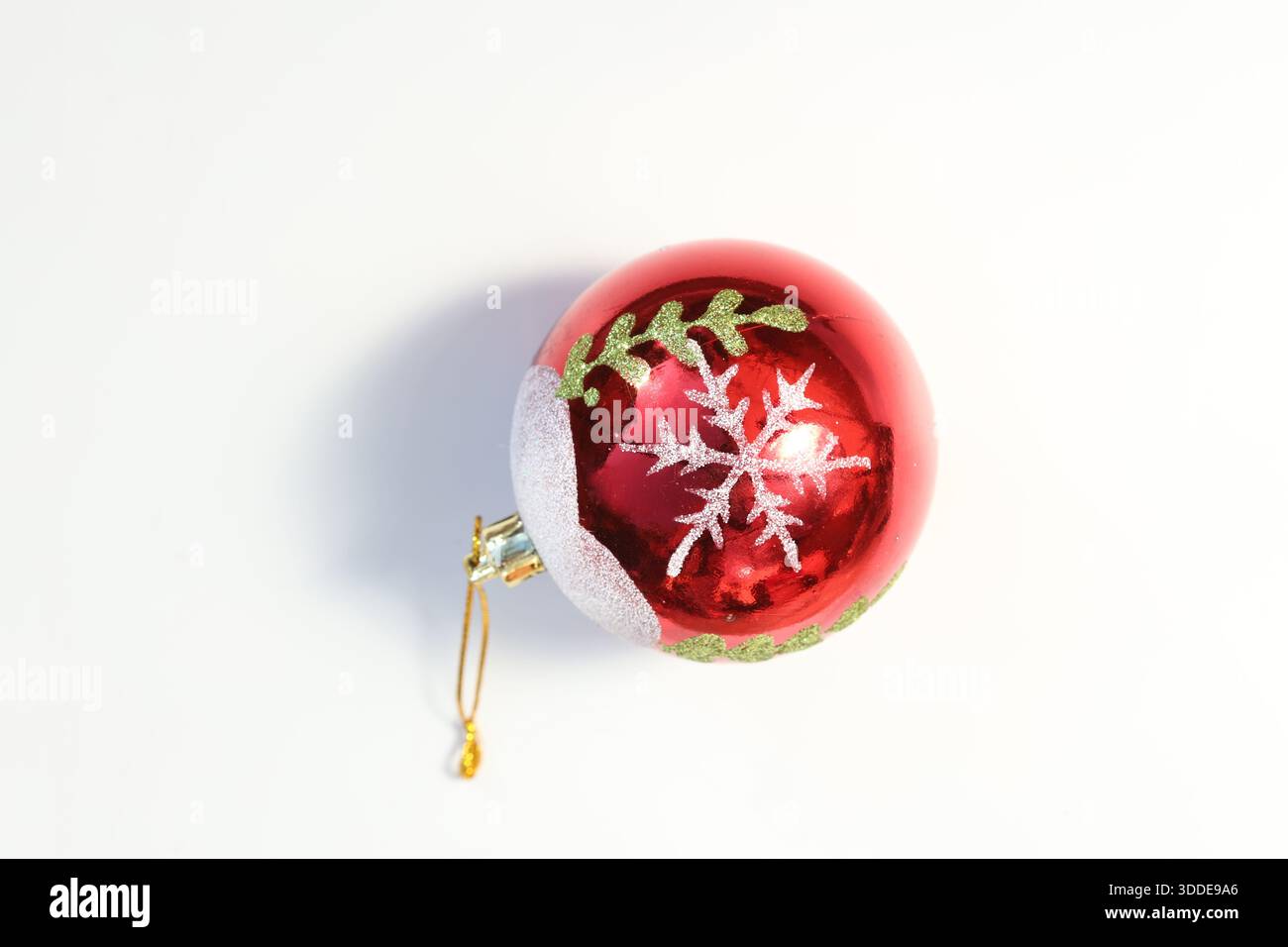 Ornement de noël rouge avec flocon de neige et feuilles vertes. Banque D'Images