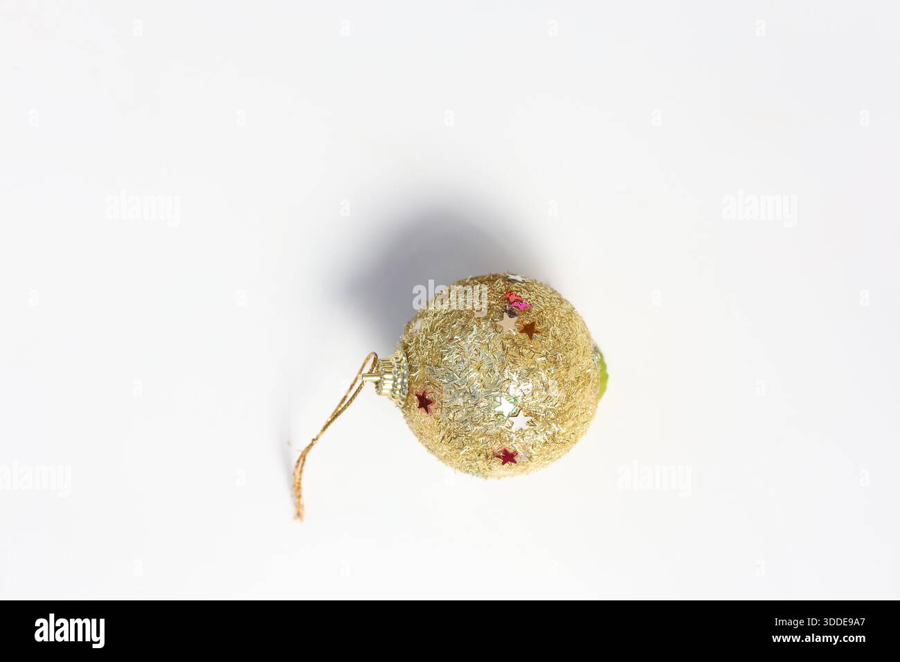 Boule dorée à paillettes avec accents rouges suspendus. Décoration de Noël isolée sur blanc Banque D'Images