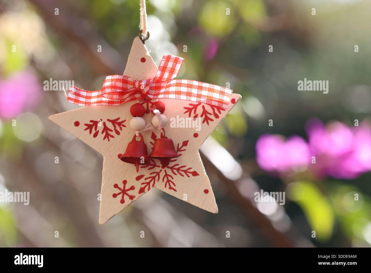 Ornement étoile avec cloches et ruban à l'extérieur. Ornement de Noël suspendu à un arbre. Banque D'Images