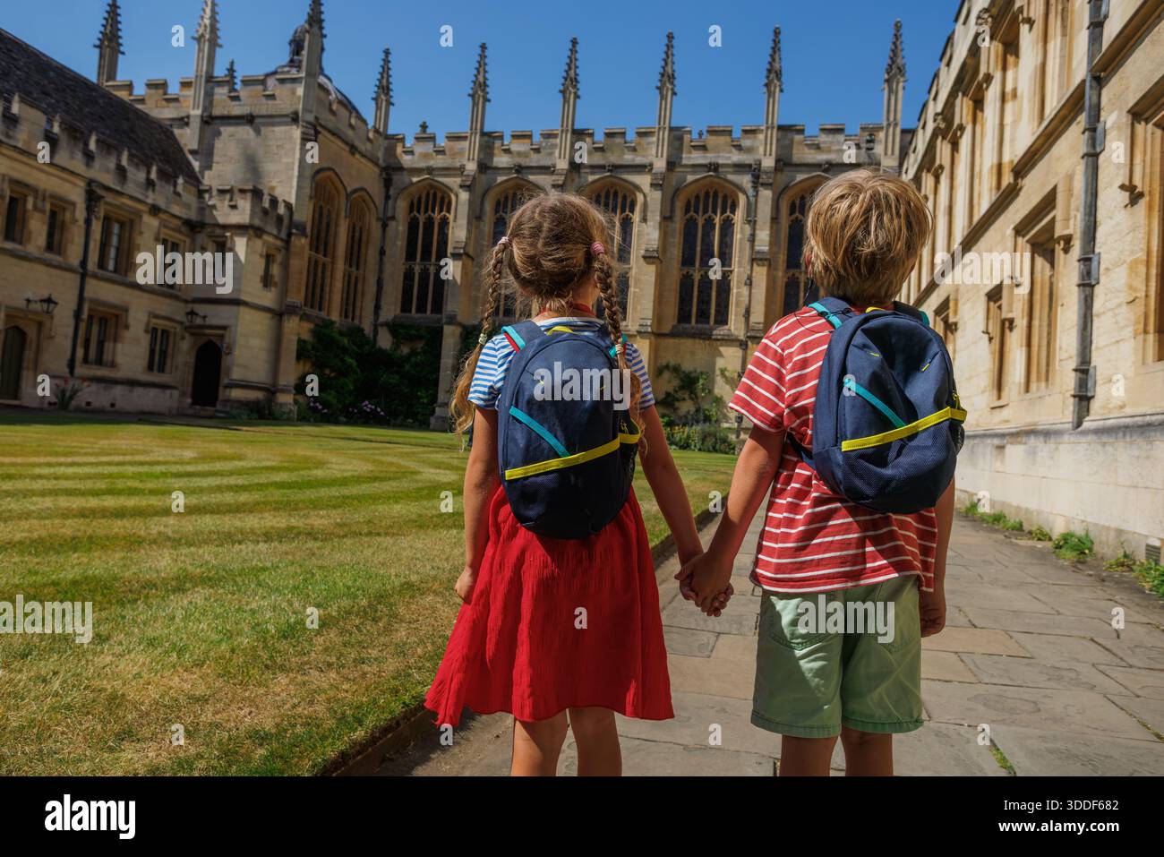 Avec des sacs à dos sur leurs épaules, deux jeunes se tiennent la main en regardant vers un grand, vieux bâtiment de All Souls College, Oxford, Grande-Bretagne Banque D'Images