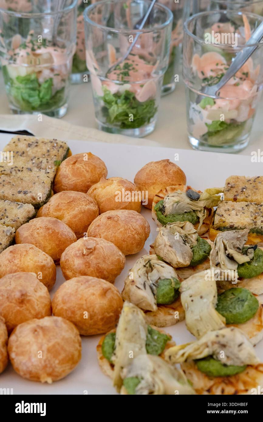 Sélection de hors-d'œuvre affichés sur une table de restauration : profiteroles dorés, canapés salés recouverts d'artichauts et de légumes Banque D'Images