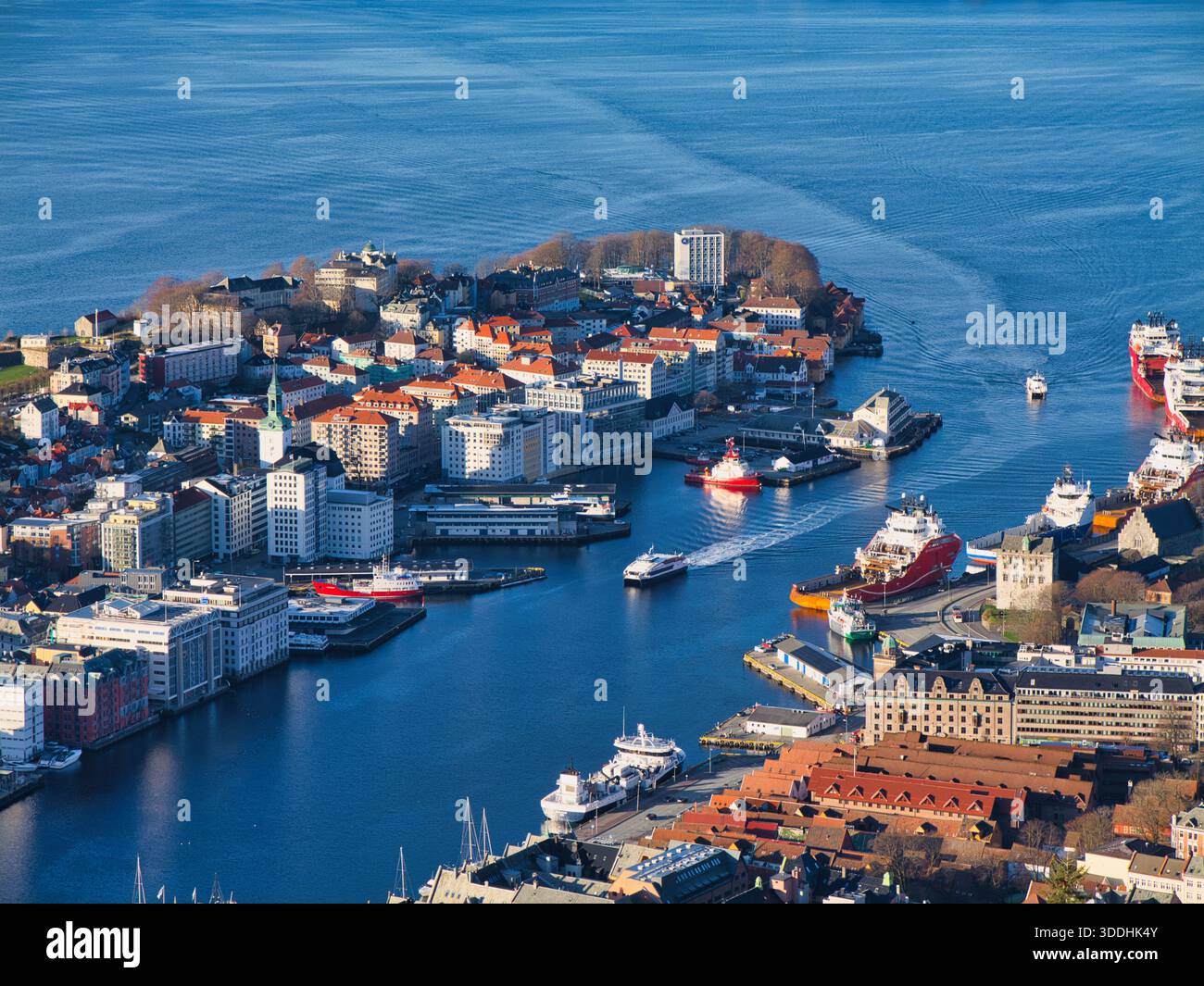 Bergen, Norvège - 14 novembre 2025 : vue surélevée sur le port de Bergen à Bergen, Norvège, avec des ferries et des navires naviguant devant des bâtiments colorés en bord de mer dans une lumière automnale éclatante. Banque D'Images