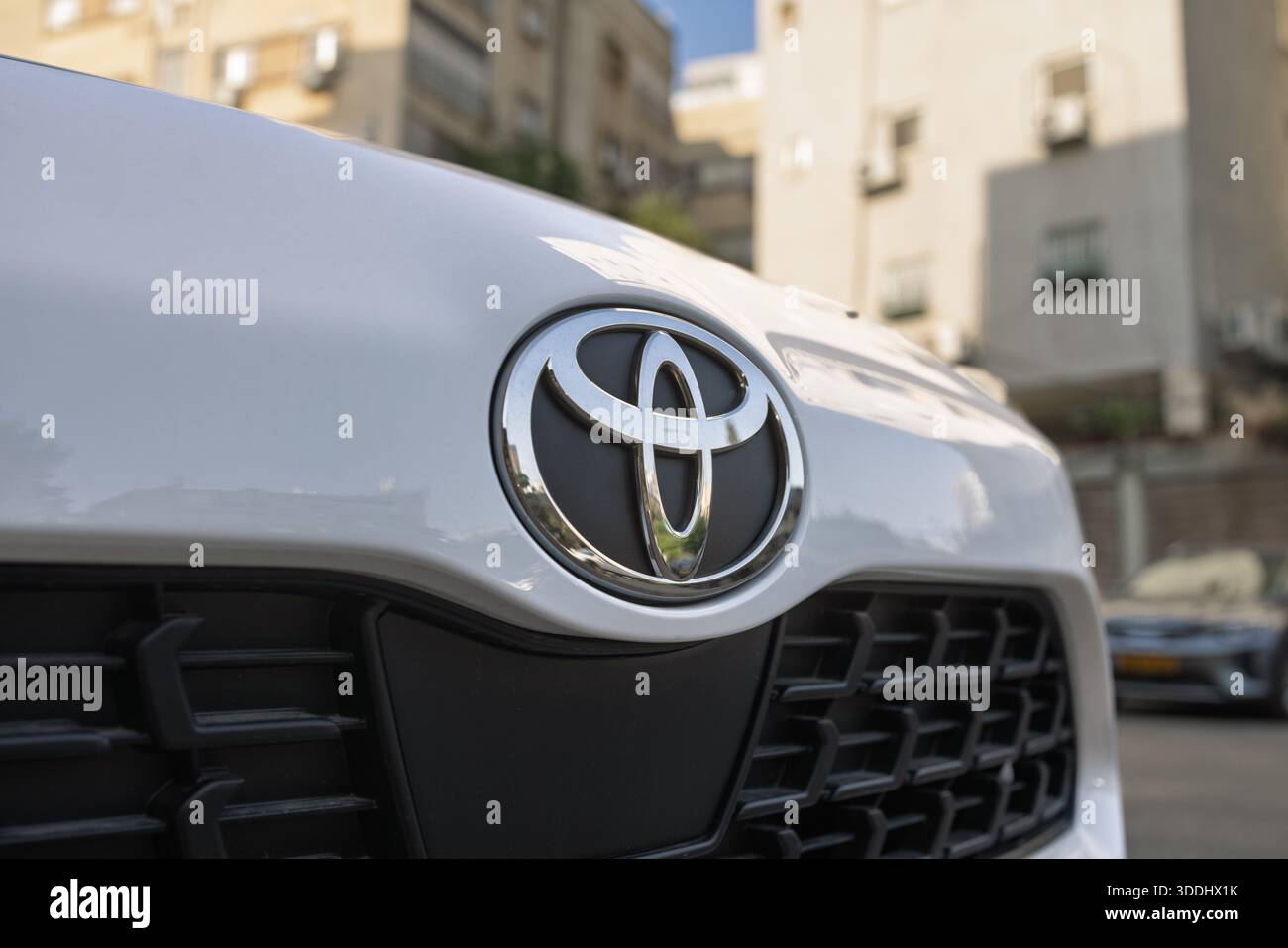 Gros plan de l'emblème Toyota argenté sur le capot avant d'une voiture blanche en milieu urbain, Givatayim, Israël, 4 décembre 2025 Banque D'Images