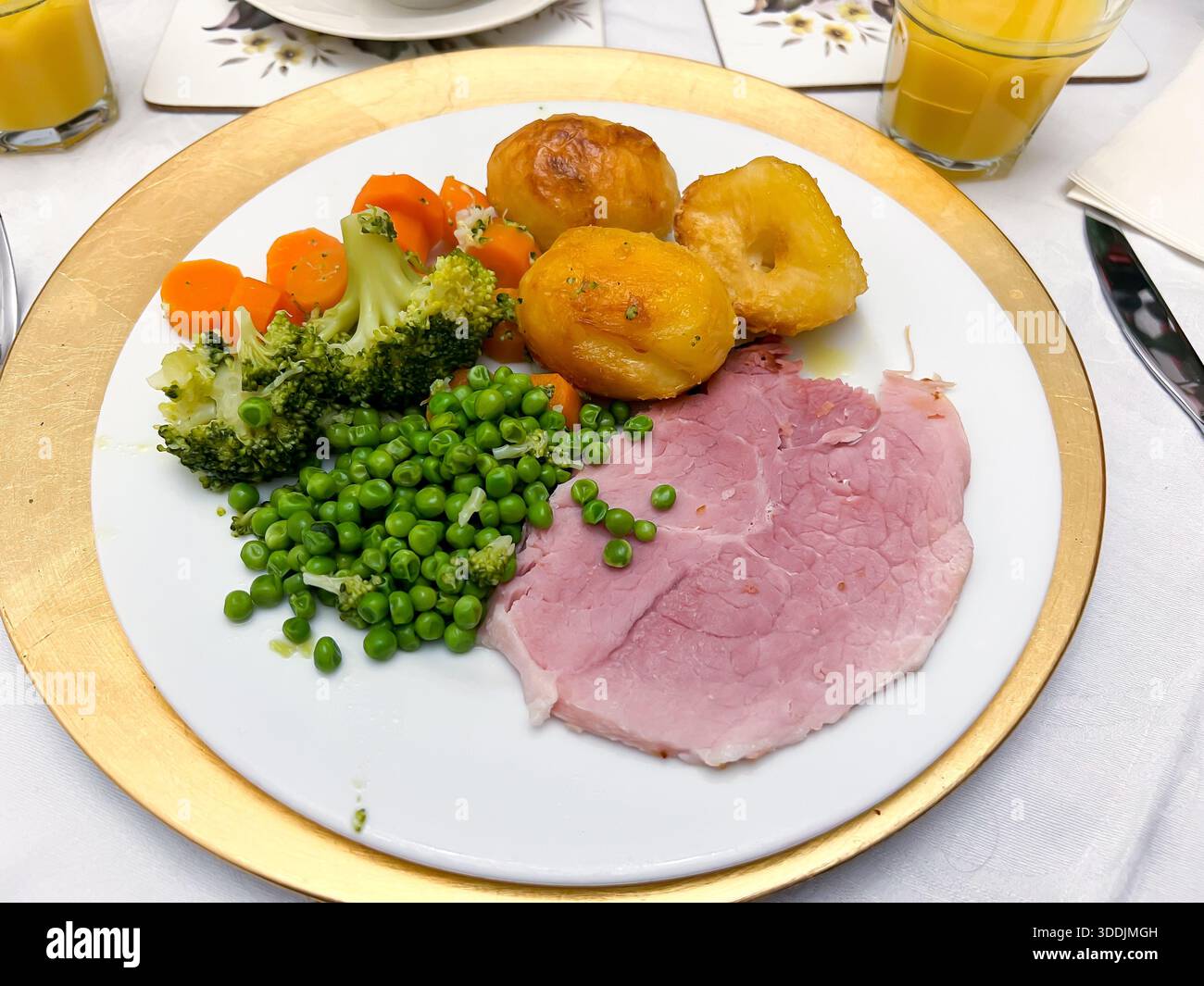 Repas de gammon rôti avec pommes de terre rôties, pois, carottes, brocoli et pousses dans une assiette. - Image de stock capturée avec un smartphone
