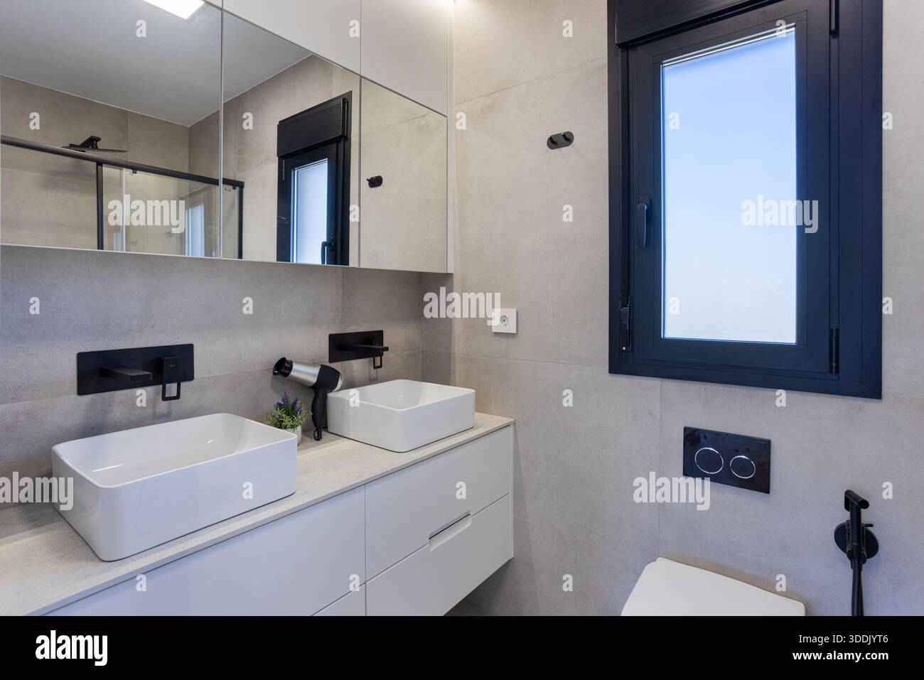 Salle de bains minimaliste contemporaine avec deux lavabos, robinets noirs élégants et grandes armoires à miroirs Banque D'Images