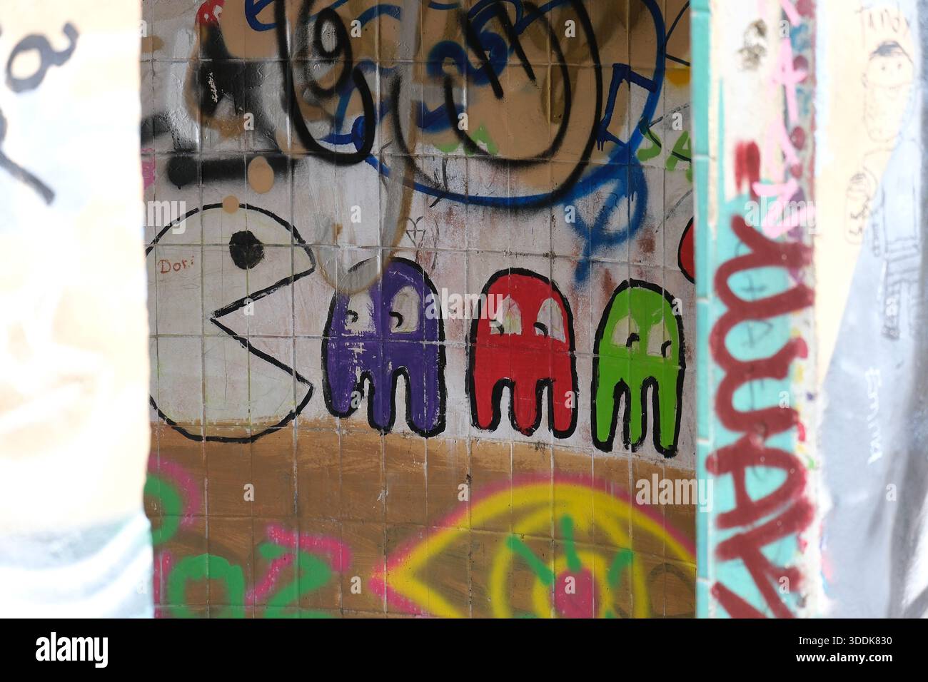 Graffiti coloré sur un mur carrelé à Jaco, Costa Rica, montrant des personnages urbains ludiques et des textures de Street art superposées. Banque D'Images