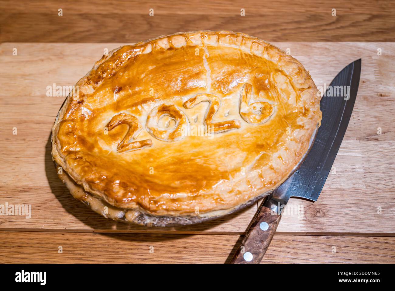Tarte maison du jour de l'an avec 2026 dans la pâte feuilletée sur la table de salle à manger avec couteau japonais Banque D'Images