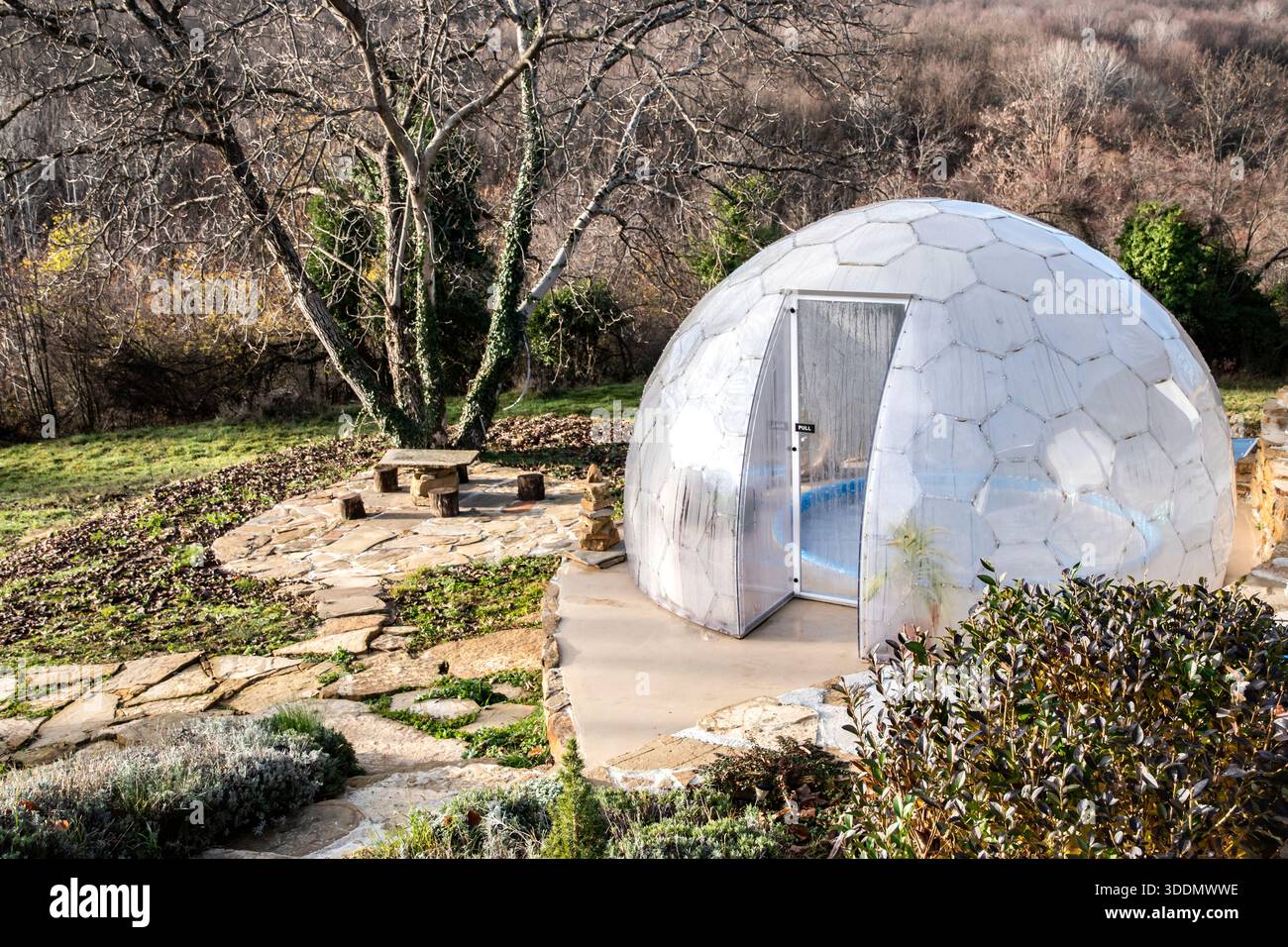 Dôme transparent en polycarbonate couvrant jacuzzi extérieur dans le jardin de la villa de montagne, abri spa moderne dans le paysage d'hiver ensoleillé Banque D'Images