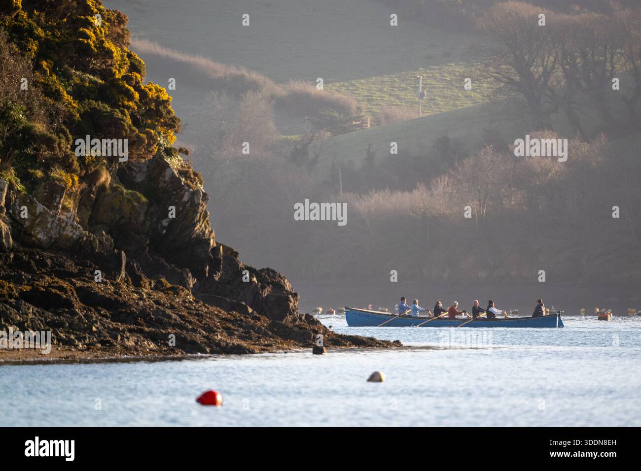 L'équipage du club d'aviron de l'estuaire de Salcombe est sorti sur une sortie matinale dans leur bateau d'aviron de concert avec la lumière du matin magnifique les attraper. Banque D'Images