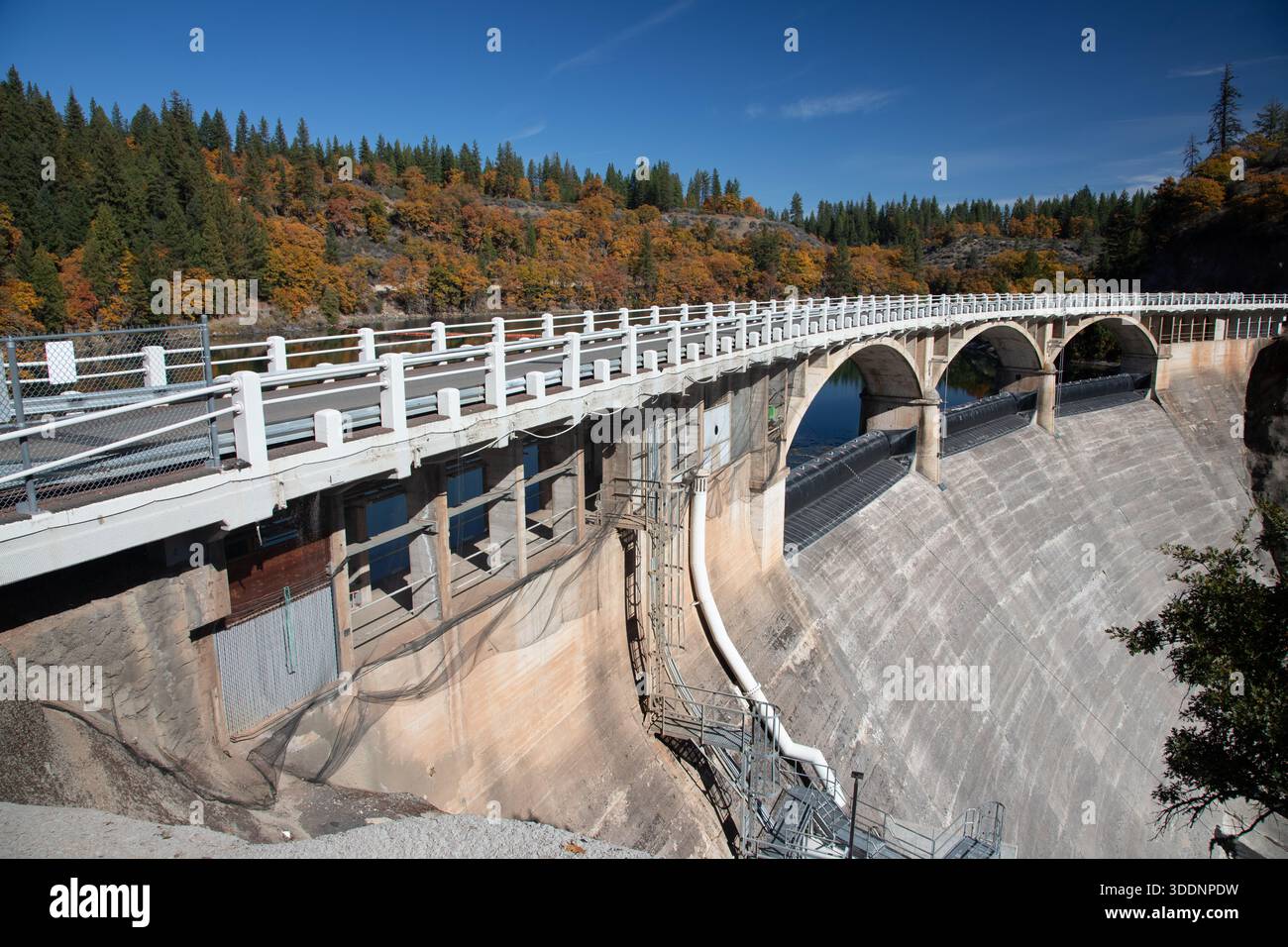 Barrage en voûte en béton Pit 3 enjambant la rivière Pit au lac Britton en automne, avec des garde-corps, un déversoir incurvé et un feuillage d'automne coloré dans le comté de Shasta, Banque D'Images