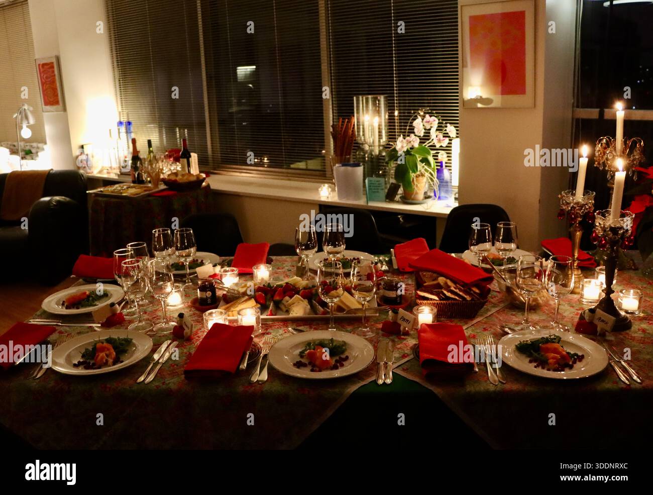Table de dîner de Noël, nappe, bougies avec des ornements, serviettes rouges, premier plat pré-plaqué, en attente des invités du dîner à un repas de fête. Banque D'Images