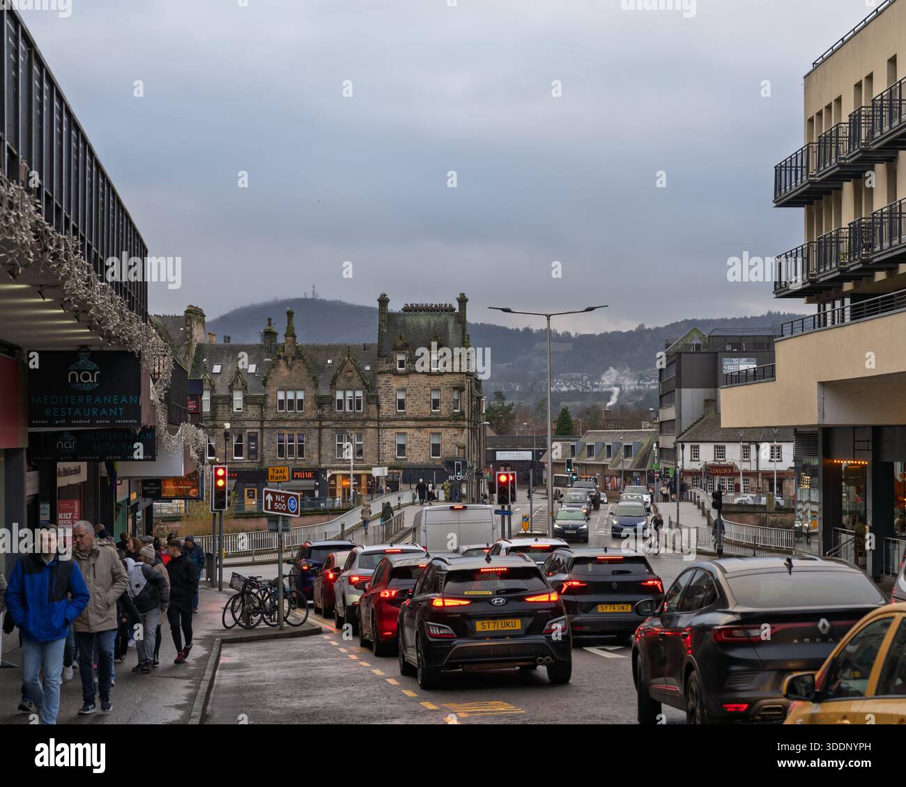 Bridge Street à Inverness menant au pont Ness sur la rivière Spey. Les gens marchent le long de la rue pendant que les voitures passent un jour gris de décembre. Banque D'Images