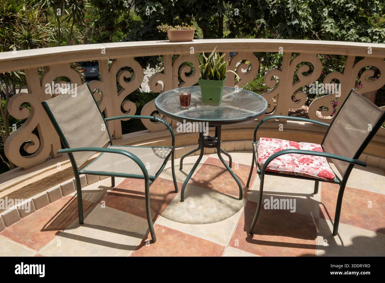 Balcon ensoleillé coin salon avec table et chaises en verre dans un jardin du Caire, Egypte Banque D'Images