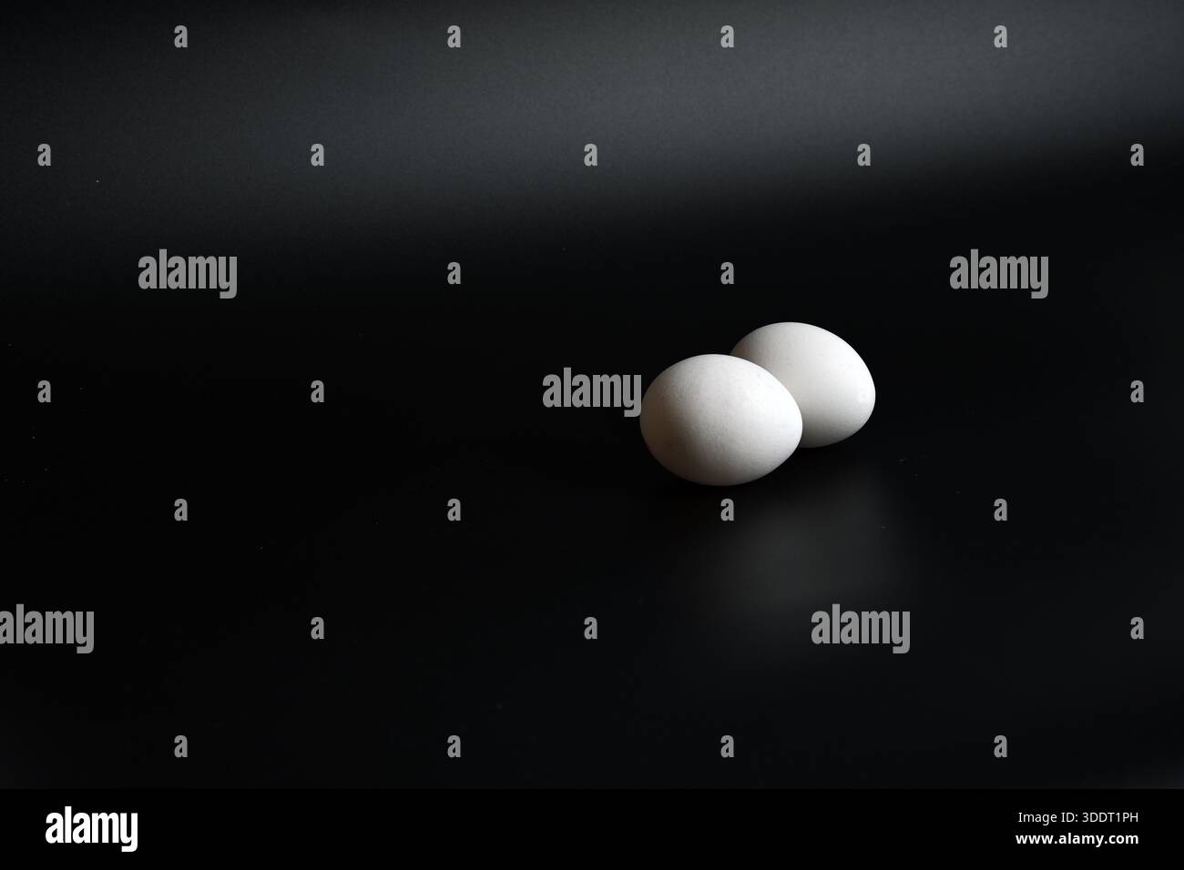 Concept de petit déjeuner minimaliste avec deux œufs blancs sur une petite soucoupe, lumière haute et basse. Banque D'Images