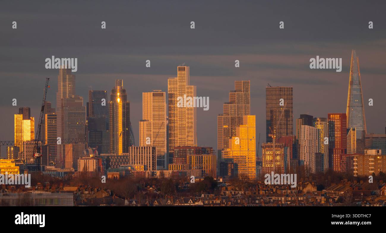Wimbledon, Londres, Royaume-Uni. 3 janvier 2026. Panorama des gratte-ciels de la ville de Londres brillants or au coucher du soleil avec des propriétés résidentielles de faible hauteur au premier plan. Crédit : Malcolm Park/Alamy Live News Banque D'Images