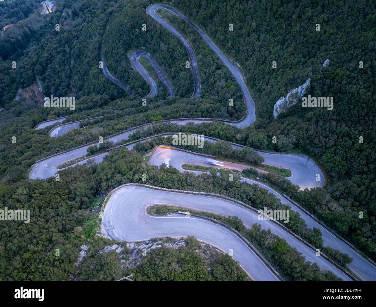 Vue aérienne de haut en bas de la route de montagne sinueuse avec virages en épingle à cheveux et sentiers légers au crépuscule à Sokraki, Corfou, Grèce Banque D'Images