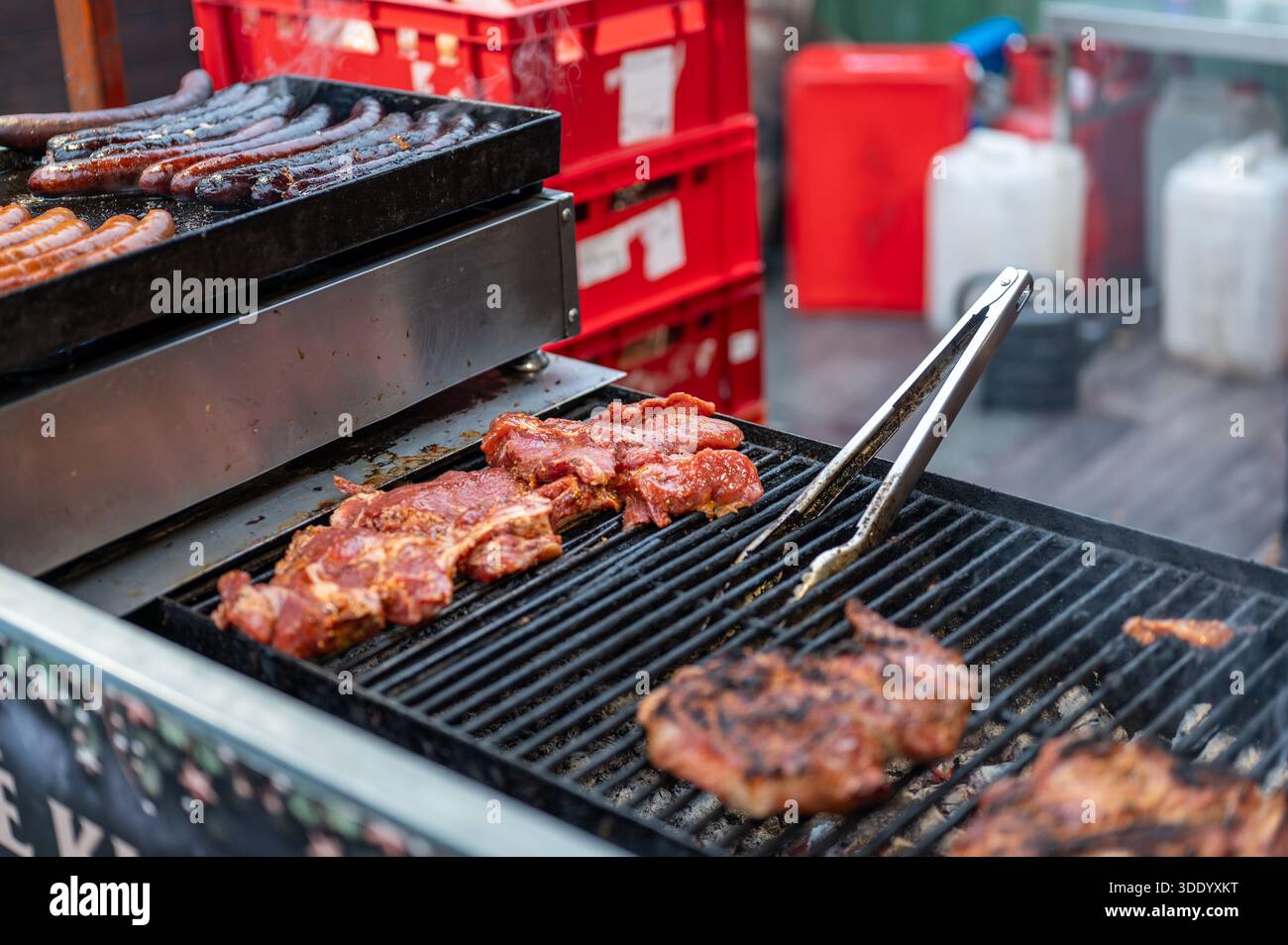 Vue rapprochée du grill au marché de noël avec saucisses et cuisson de viande sur charbons chauds, scène de Street food avec fumée, chaleur et victoire traditionnelle Banque D'Images
