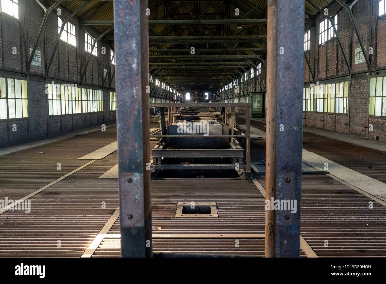 Vue de machines industrielles abandonnées vues à travers un cadre métallique à l'intérieur d'une salle d'usine déserte mettant en évidence la géométrie et la profondeur Banque D'Images