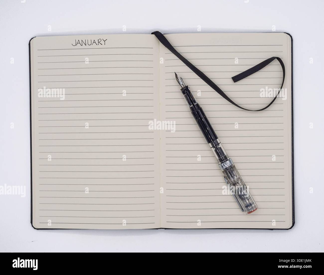 Vue de haut en bas d'un carnet ouvert avec un en-tête de planification de janvier, un stylo plume transparent et un marqueur ruban noir sur une surface blanche propre. Banque D'Images