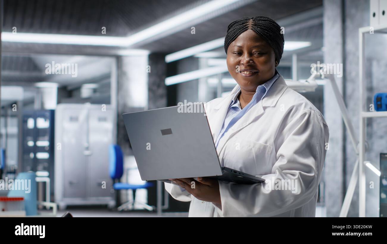 Afro-américaine scientifique travaille dans un laboratoire moderne, menant des expériences avec des équipements de pointe et un ordinateur portable. Biologie moléculaire, biotechnologie et innovation dans le domaine de la santé. Banque D'Images