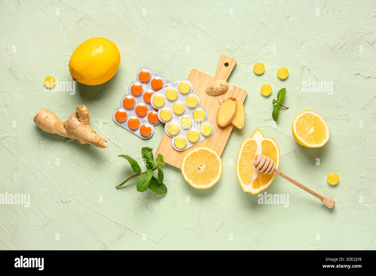 Gouttes de toux dans des cloques avec des citrons, des feuilles de menthe et de la racine de gingembre sur fond vert Banque D'Images