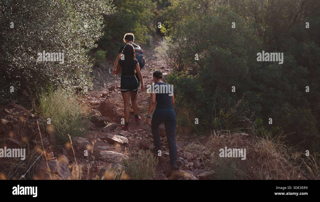 Les gens marchent un chemin rocheux en montée à travers une végétation luxuriante et sèche Banque D'Images