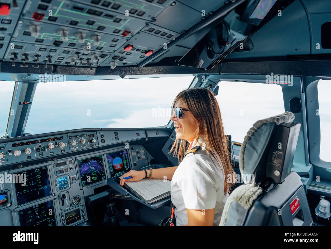 Pilote féminin heureux souriant à l'intérieur du cockpit de l'avion en vol Banque D'Images