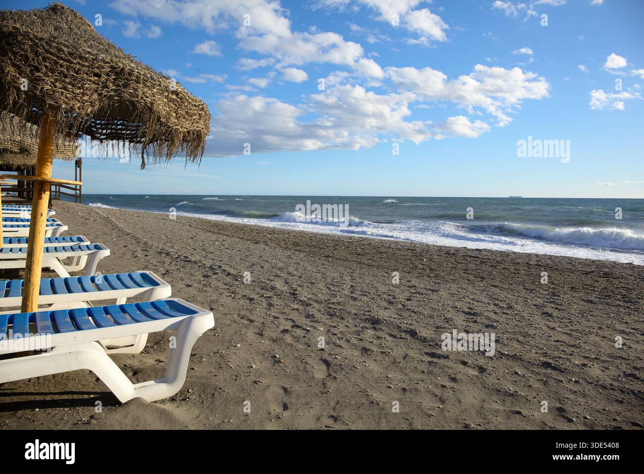 Chaises longues et parasols le long d'une plage vide sur la Costa del sol près de Malaga, Espagne Banque D'Images