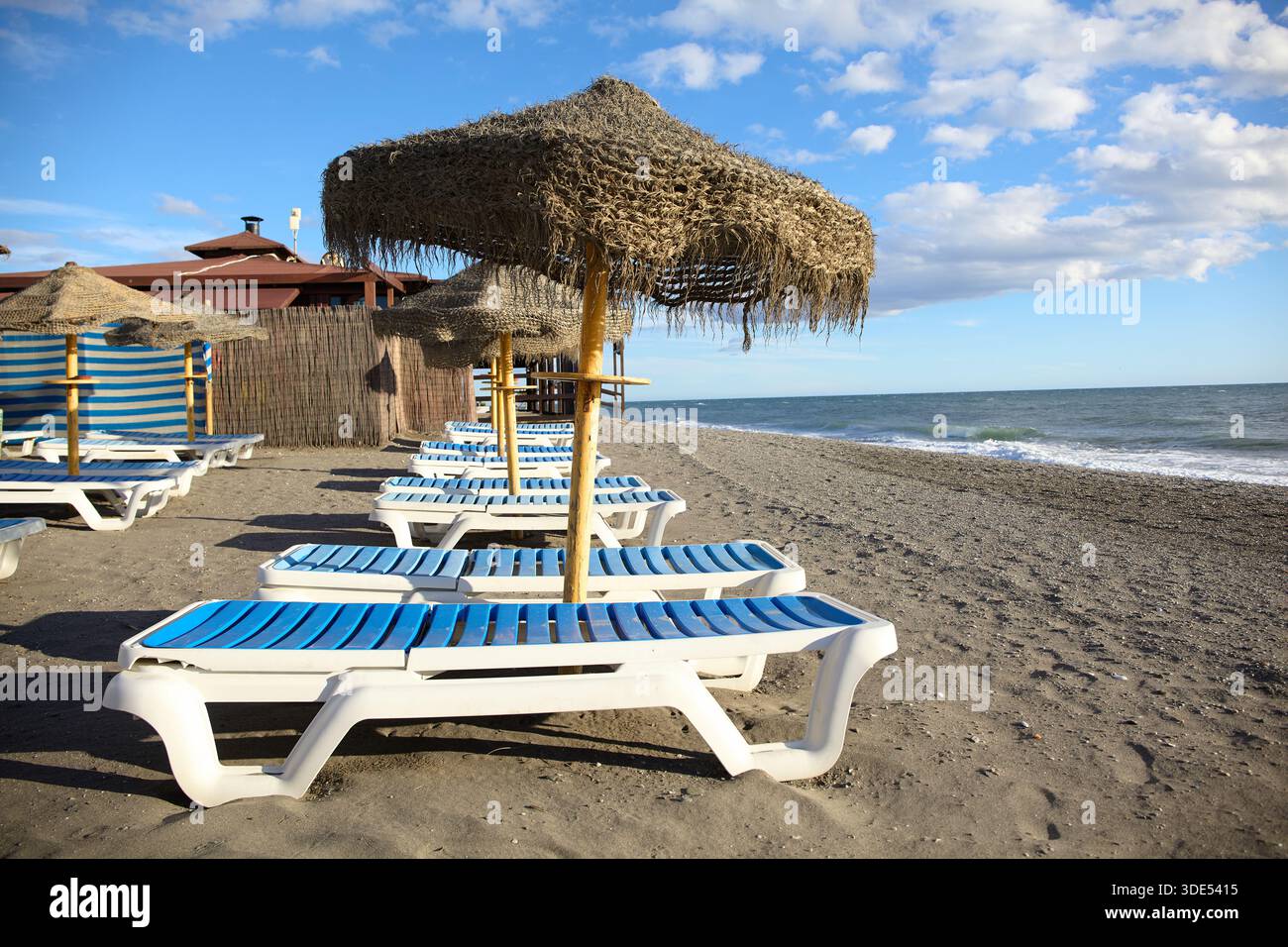 Chaises longues et parasols le long d'une plage vide sur la Costa del sol près de Malaga, Espagne Banque D'Images