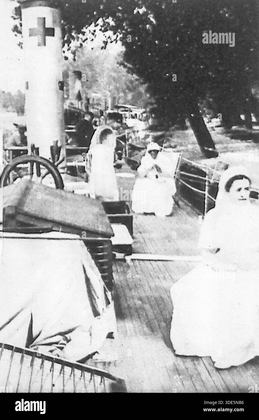 Cette photographie d'archives de 1914 du miroir présente un bateau de plaisance autrefois propriété de la célèbre actrice française Lantelme, aujourd'hui réaffecté à l'effort de guerre. Faisant partie d'une flottille fluviale spécialisée, le navire est utilisé pour évacuer les soldats blessés, offrant un niveau de confort bien supérieur à celui des trains médicaux standard. L'image montre des infirmières de la Croix-Rouge sur le pont, soulignant la mobilisation créative des ressources civiles et de l'artisanat de luxe pour fournir de l'aide humanitaire pendant la Grande Guerre. Banque D'Images