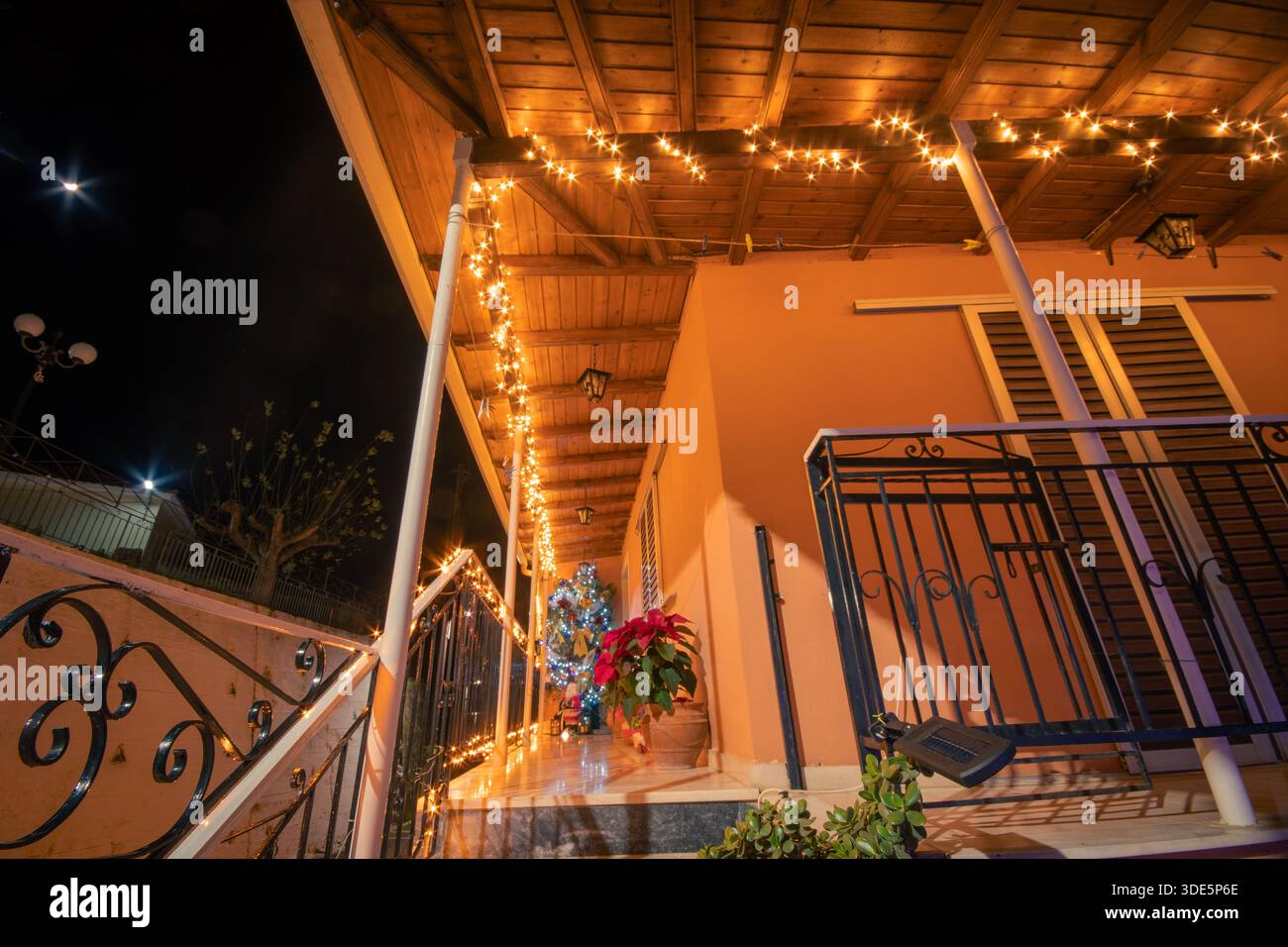 Vue en angle bas de Noël décoré porche et escalier avec des lumières à cordes et des plantes poinsettia sur un extérieur de maison orange à Corfou en Grèce Banque D'Images