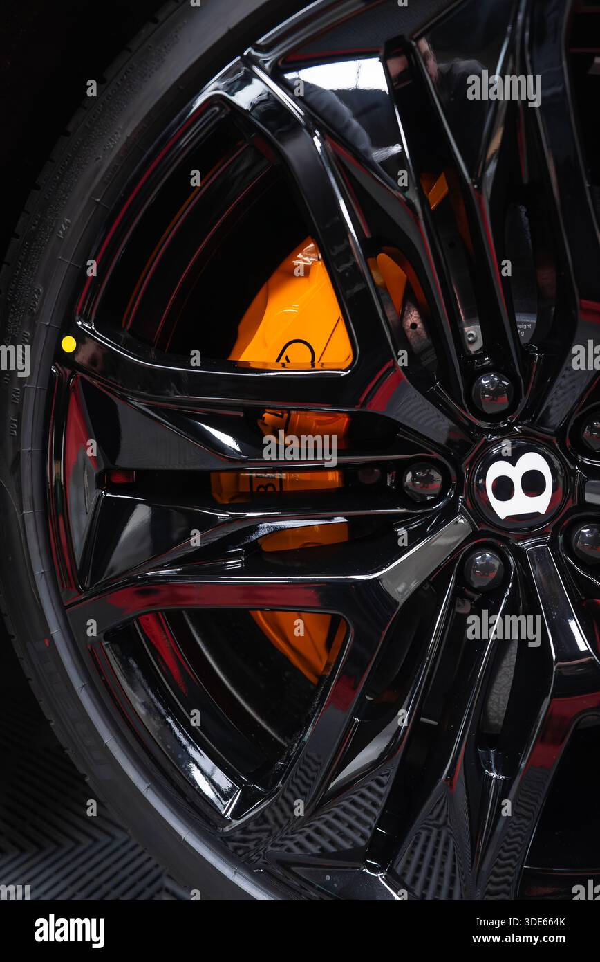 Gros plan d'une roue multi-rayons noir brillant sur une Bentley Bentayga Speed, étrier de frein orange vif et disque ventilé visible, avec un Bala jaune Banque D'Images
