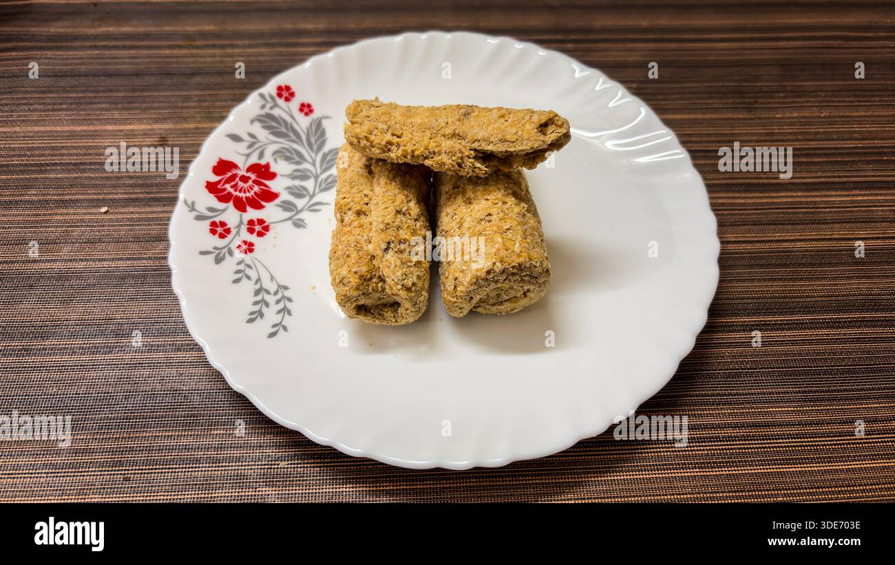friandises indiennes traditionnelles au sésame cassantes ou tilkut servies sur une plaque en céramique blanche vue de dessus Banque D'Images