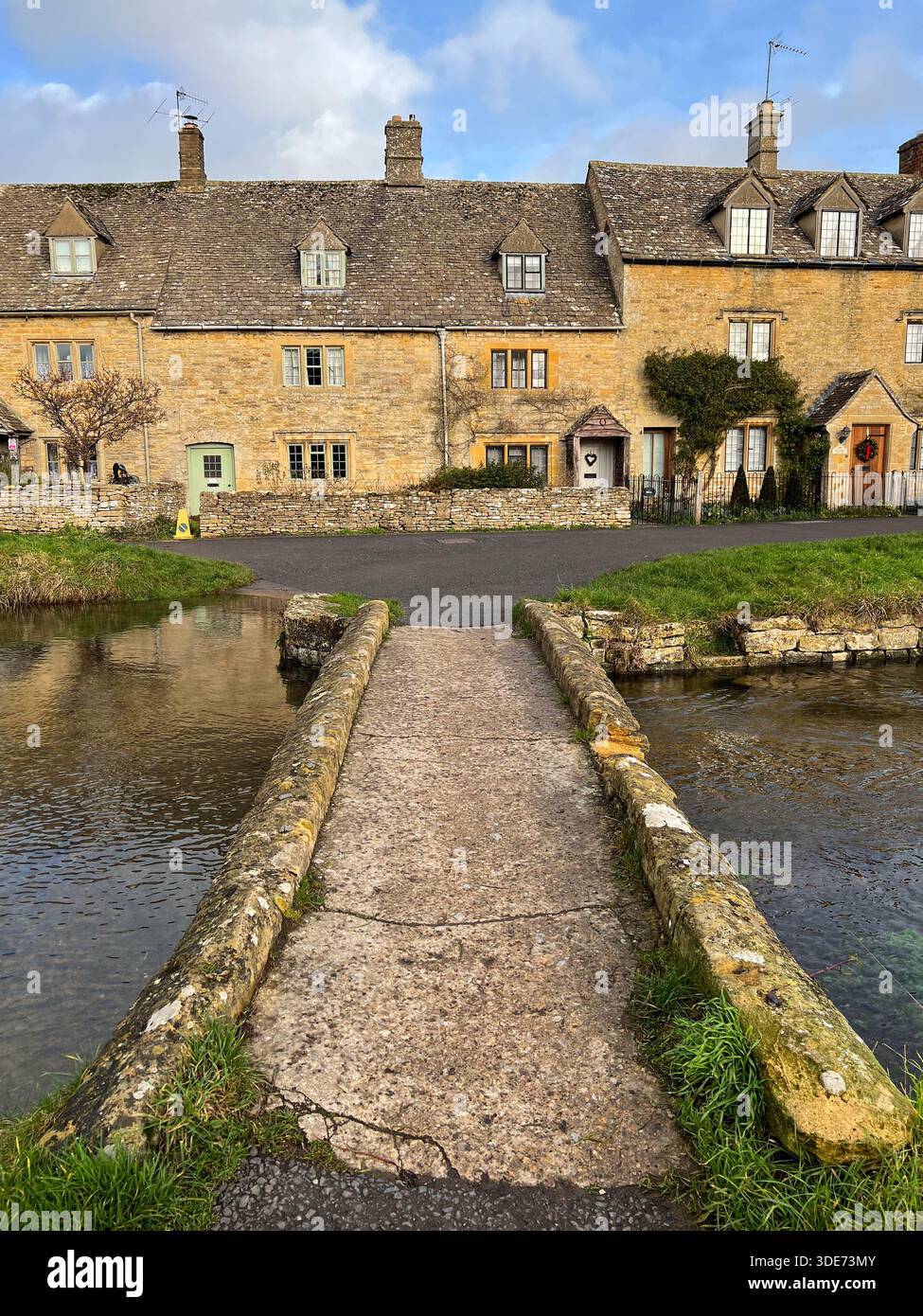 Charmante passerelle en pierre au-dessus du ruisseau avec les chalets traditionnels des Cotswolds Angleterre - Image de stock capturée avec un smartphone