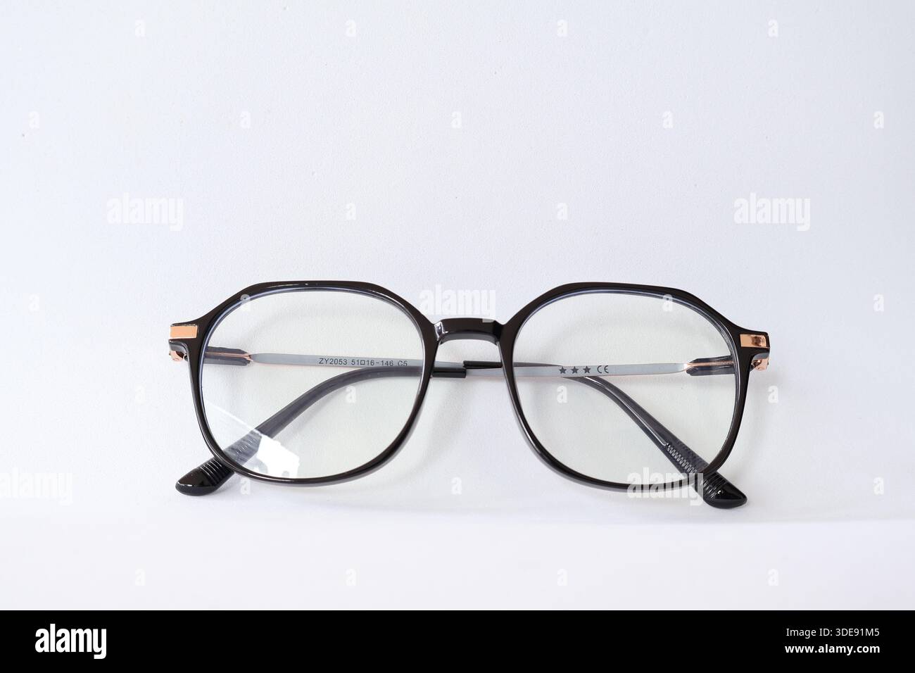 Lunettes modernes à monture noire avec détails en or rose, isolées sur fond blanc. Mode minimaliste et concept de vision. Banque D'Images