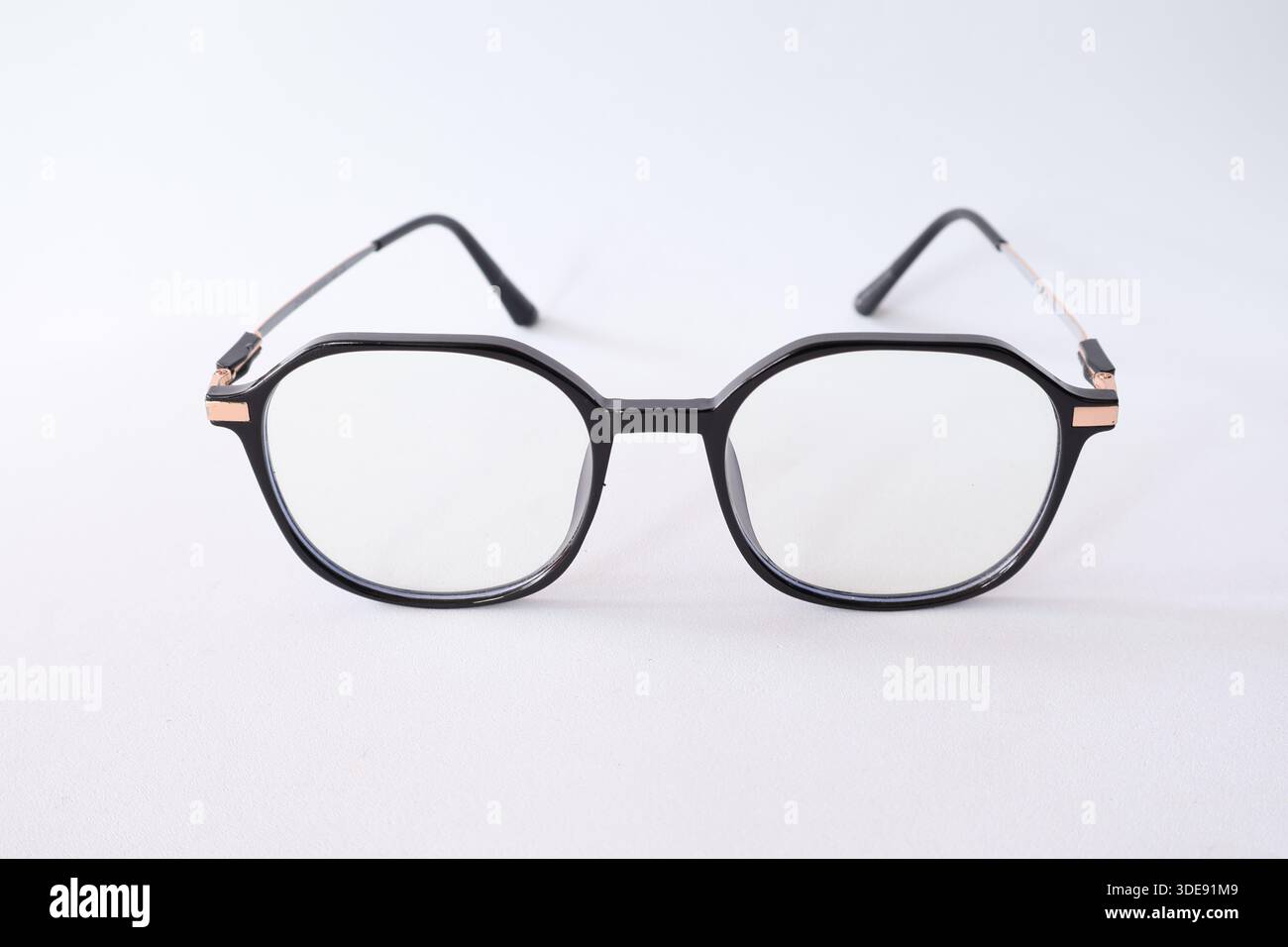 Lunettes modernes à monture noire avec détails en or rose, isolées sur fond blanc. Mode minimaliste et concept de vision. Banque D'Images