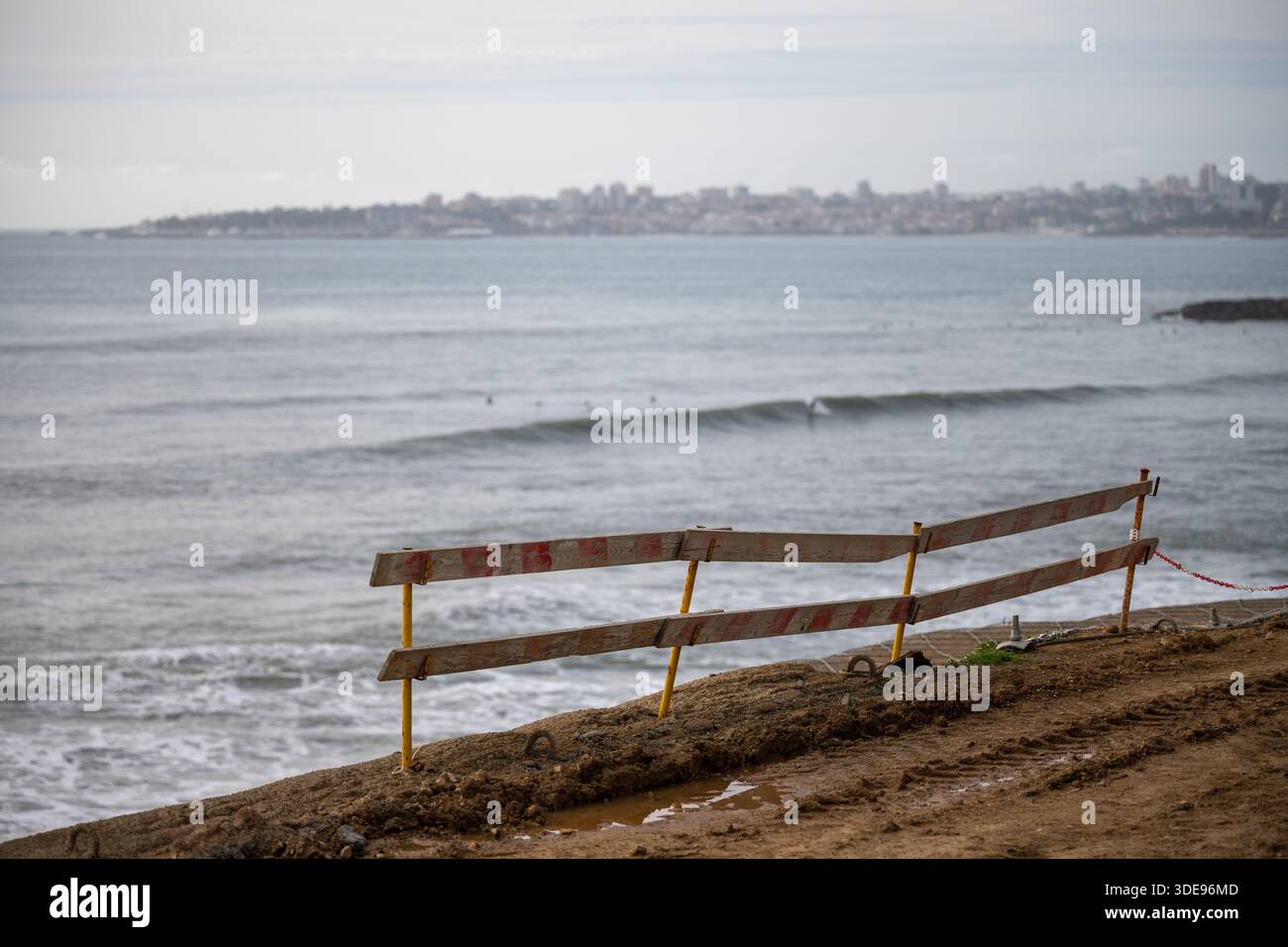 Estoril Portugal 17 décembre 2025. Une barrière de sécurité temporaire en bois se dresse le long d'un bord côtier surplombant l'océan Atlantique avec des vagues brisant BE Banque D'Images