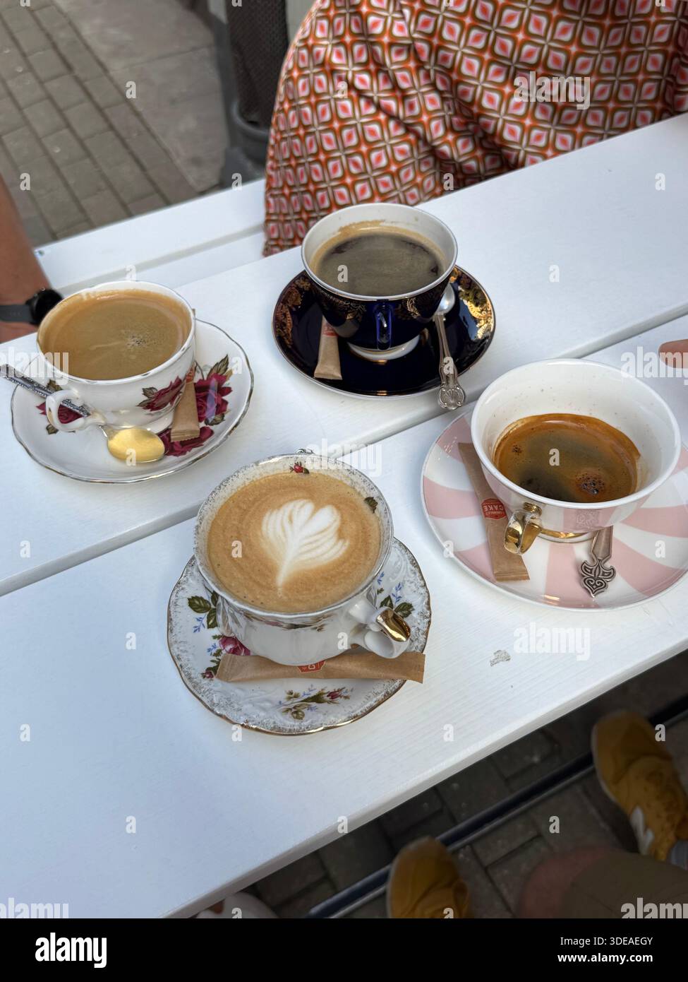 Cafés variés servis dans des tasses en porcelaine vintage sur une table blanche extérieure pendant la réunion printanière - Image de stock capturée avec un smartphone