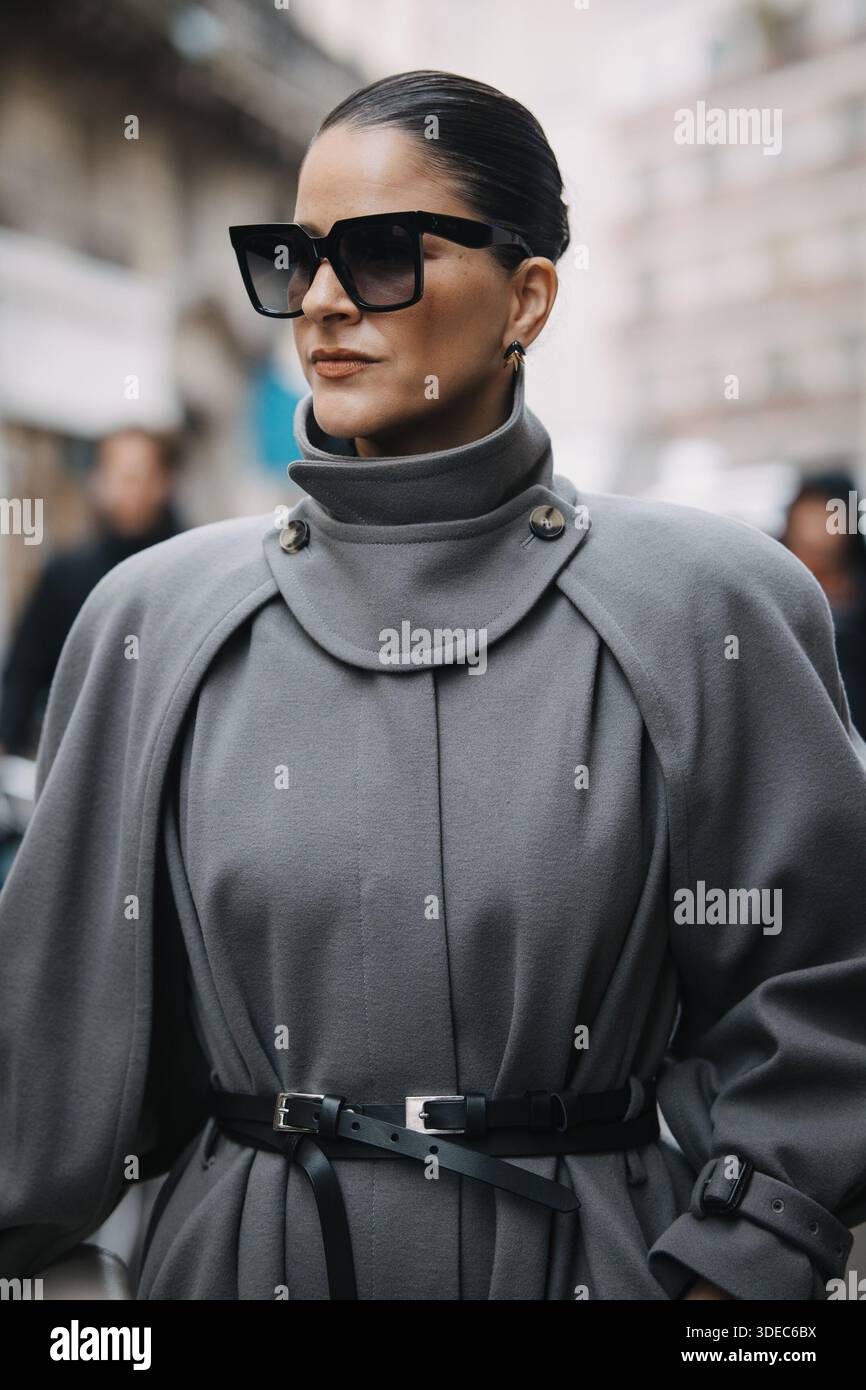 Paris, France – 11 mars 2025 : Gili Biegun porte un long trench gris avec des lunettes de soleil dans les rues de Paris pendant la semaine de la mode de Paris. Banque D'Images