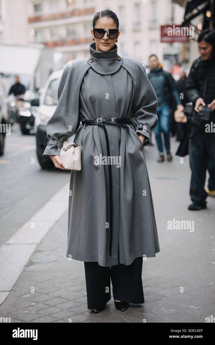 Paris, France – 11 mars 2025 : Gili Biegun porte un long trench gris avec des lunettes de soleil dans les rues de Paris pendant la semaine de la mode de Paris. Banque D'Images