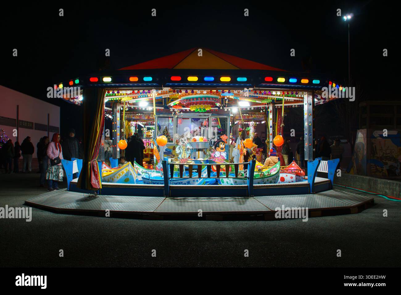 Un carrousel pour enfants bien éclairé avec des lumières colorées et des décorations la nuit lors d'une foire ou d'un événement de carnaval Banque D'Images