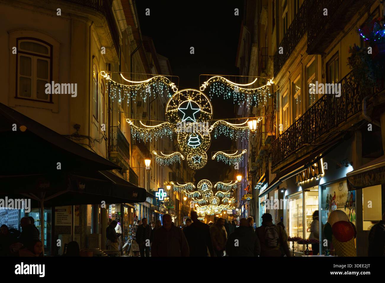 Rue piétonne bondée décorée de lumières de Noël festives et les acheteurs marchant la nuit sous des ornements suspendus et des étoiles illuminées Banque D'Images