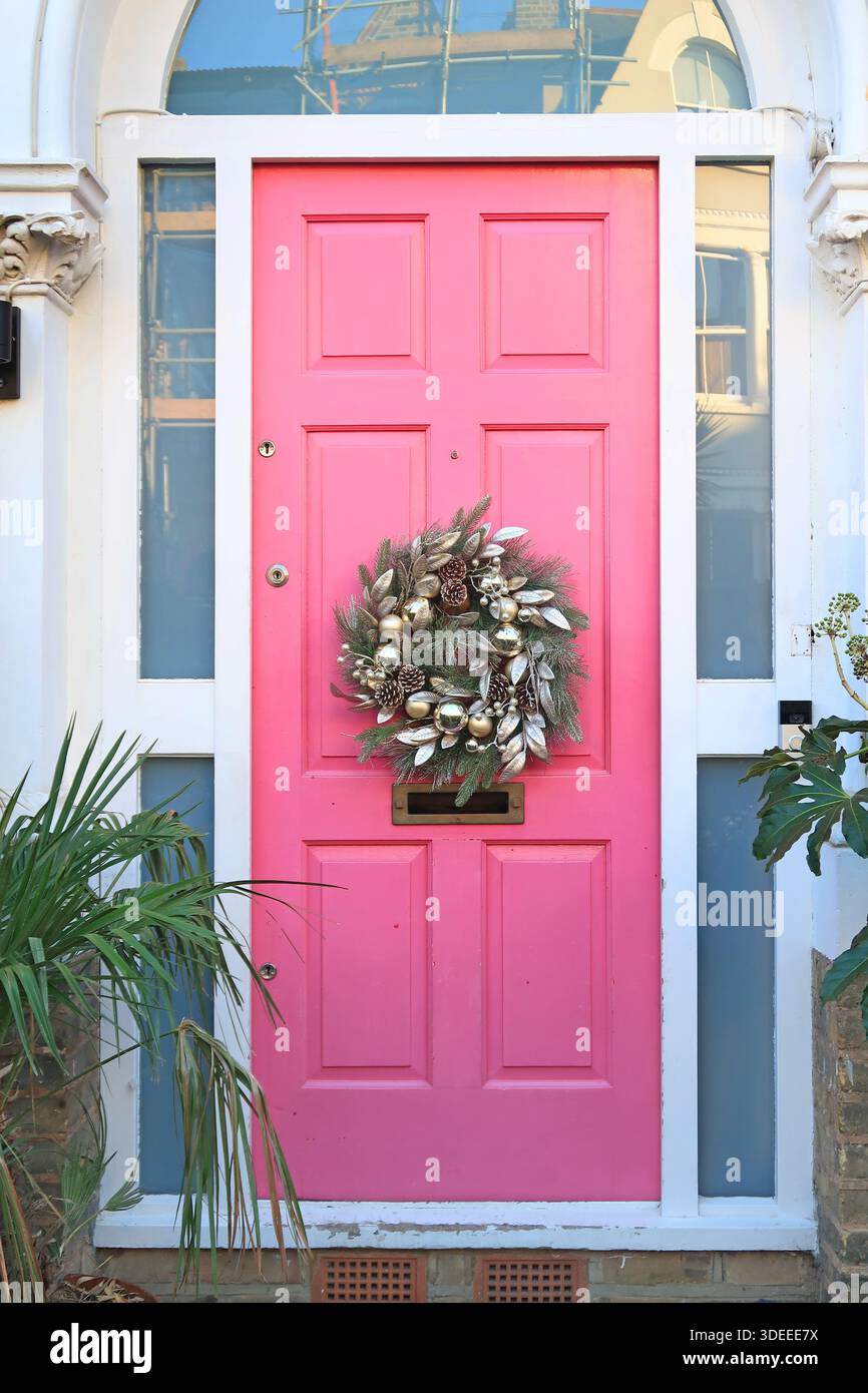 Couronne de Noël sur une porte d'entrée rose vif sur une maison victorienne dans le sud de Londres, Royaume-Uni. Banque D'Images