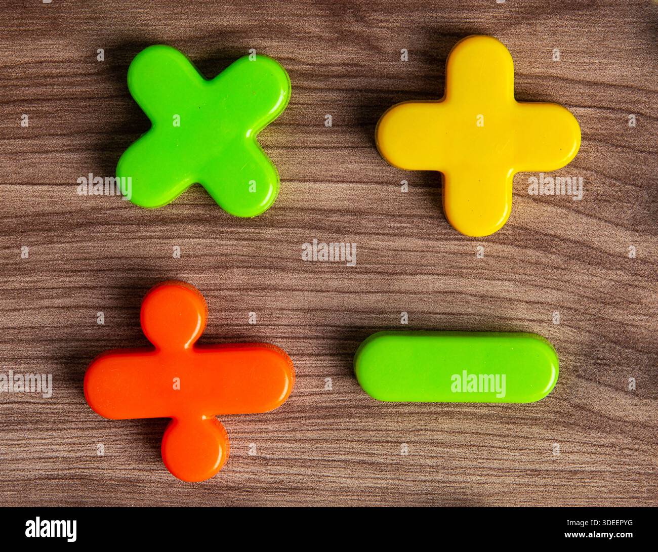 Symboles mathématiques en plastique colorés plus, moins, multiplier, diviser couché sur un fond de bois Banque D'Images