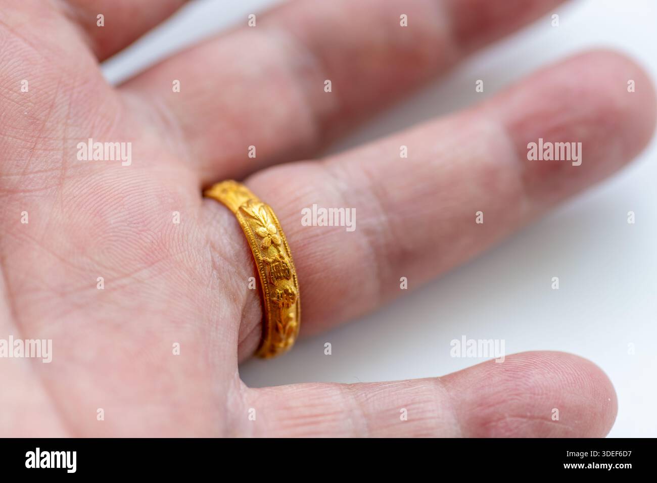 Une macro gros plan vue de la main avant d'une bague en or chinois antique sur un doigt. Banque D'Images